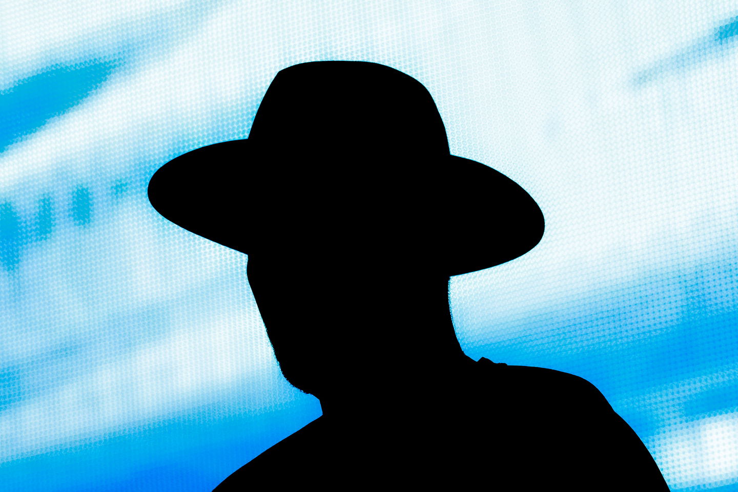 Man in front of blue screen with hat